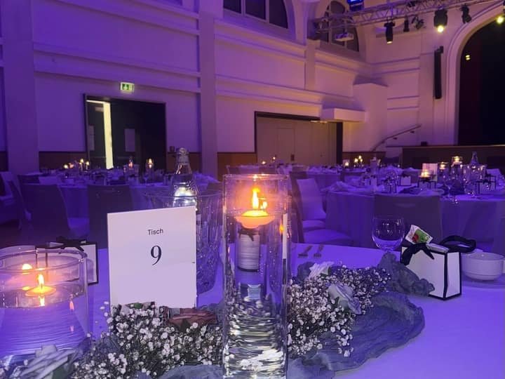 Gedeckter Tisch in einem blau beleuchteten Festsaal