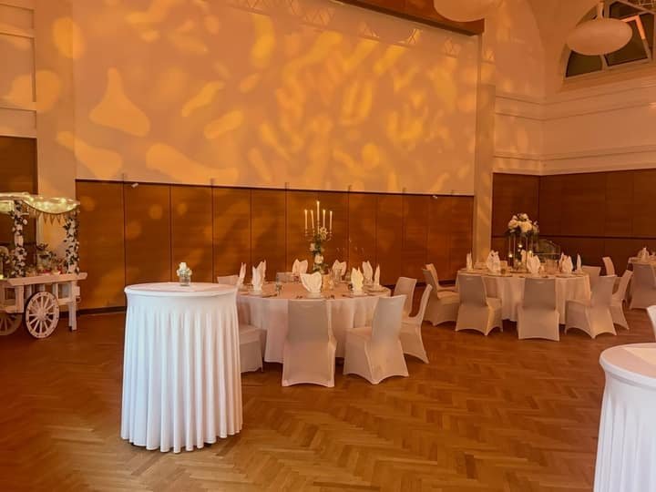 Festlich beleuchteter Saal mit gedeckten Tischen