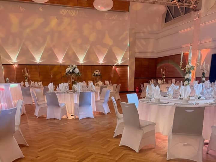 Festsaal mit warmer Lichtprojektion und Rundtischen
